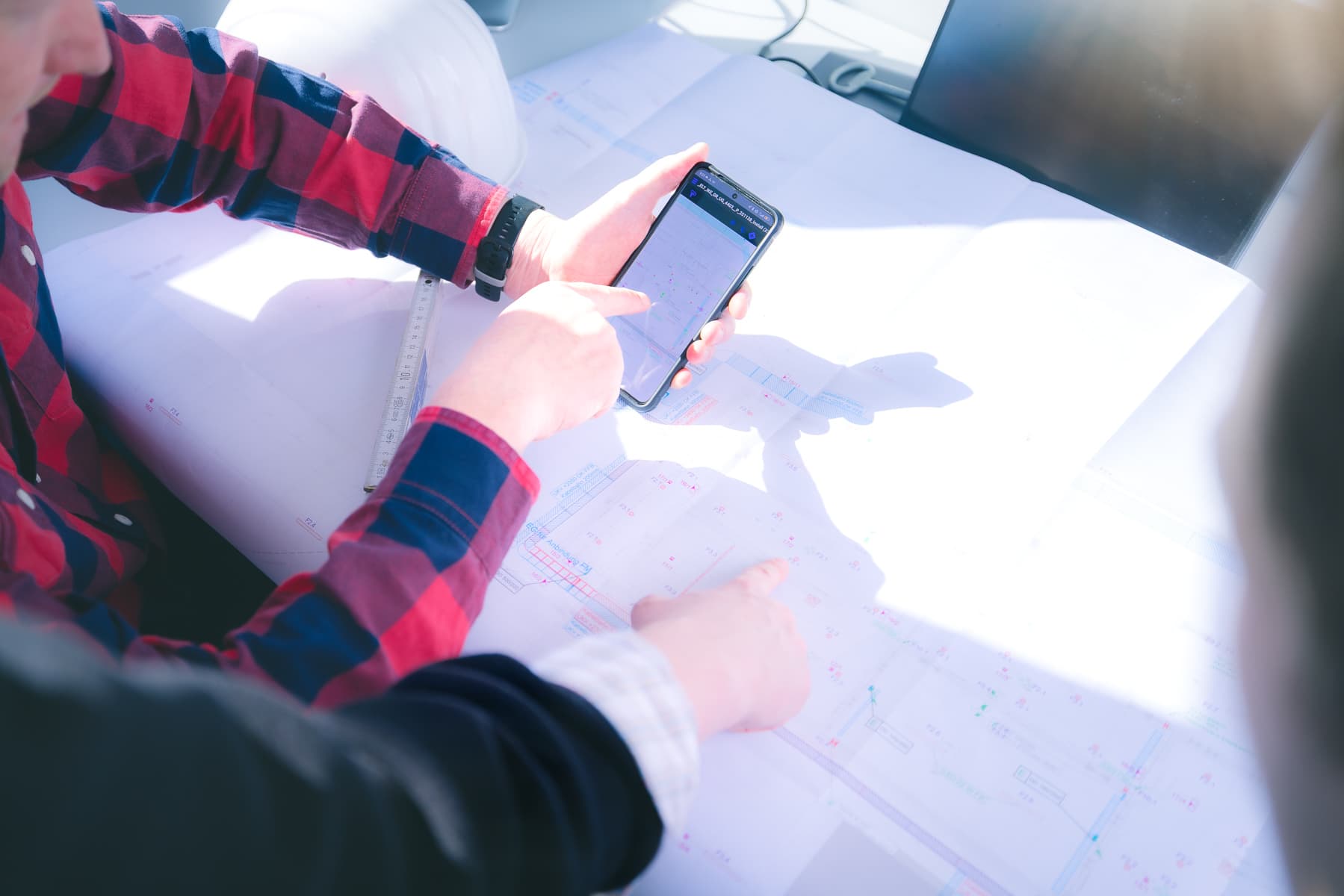 Digitale Bauplanung — Smartphone mit Plan-App über einem gedruckten Bauplan beim ik Ingenieurbüro Knoblich Dresden