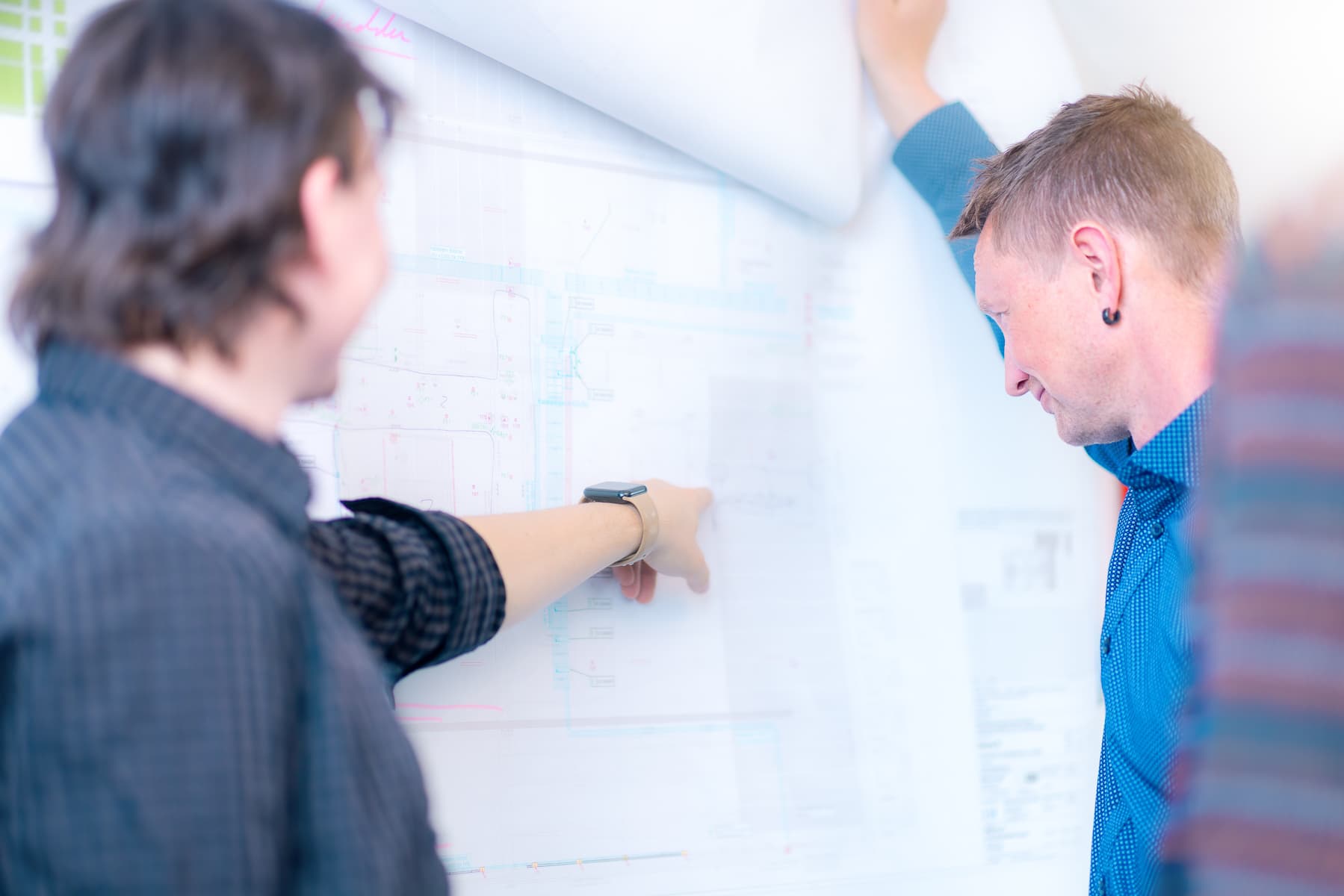 TGA-Fachplaner bei der Planabstimmung an einer Elektroplan-Wandzeichnung beim ik Ingenieurbüro Knoblich Dresden